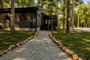 A cabin with a gravel path leading to the entrance, surrounded by trees. - Lakefront Cabin with Two Decks and Back Yard in Tennessee (Tracy City)