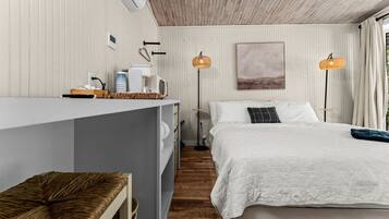 A bedroom with a bed, bedside tables, a desk, and a lamp.