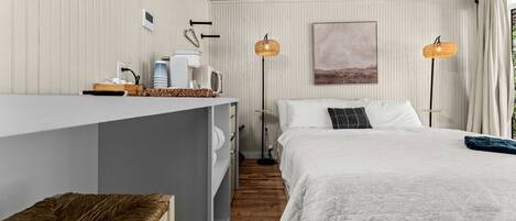 A bedroom with a bed, bedside tables, a desk, and a lamp.