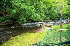 A hammock overlooking a flowing river in a forested area.