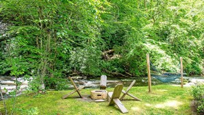 A hammock, a wooden chair, and a fire pit in a forested area. - Stunning Yurt with Magnificent Creek Views in Topton, North Carolina (Topton)