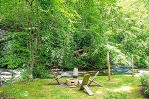 Eine Hängematte, ein Holzstuhl und eine Feuerstelle in einem bewaldeten Gebiet.