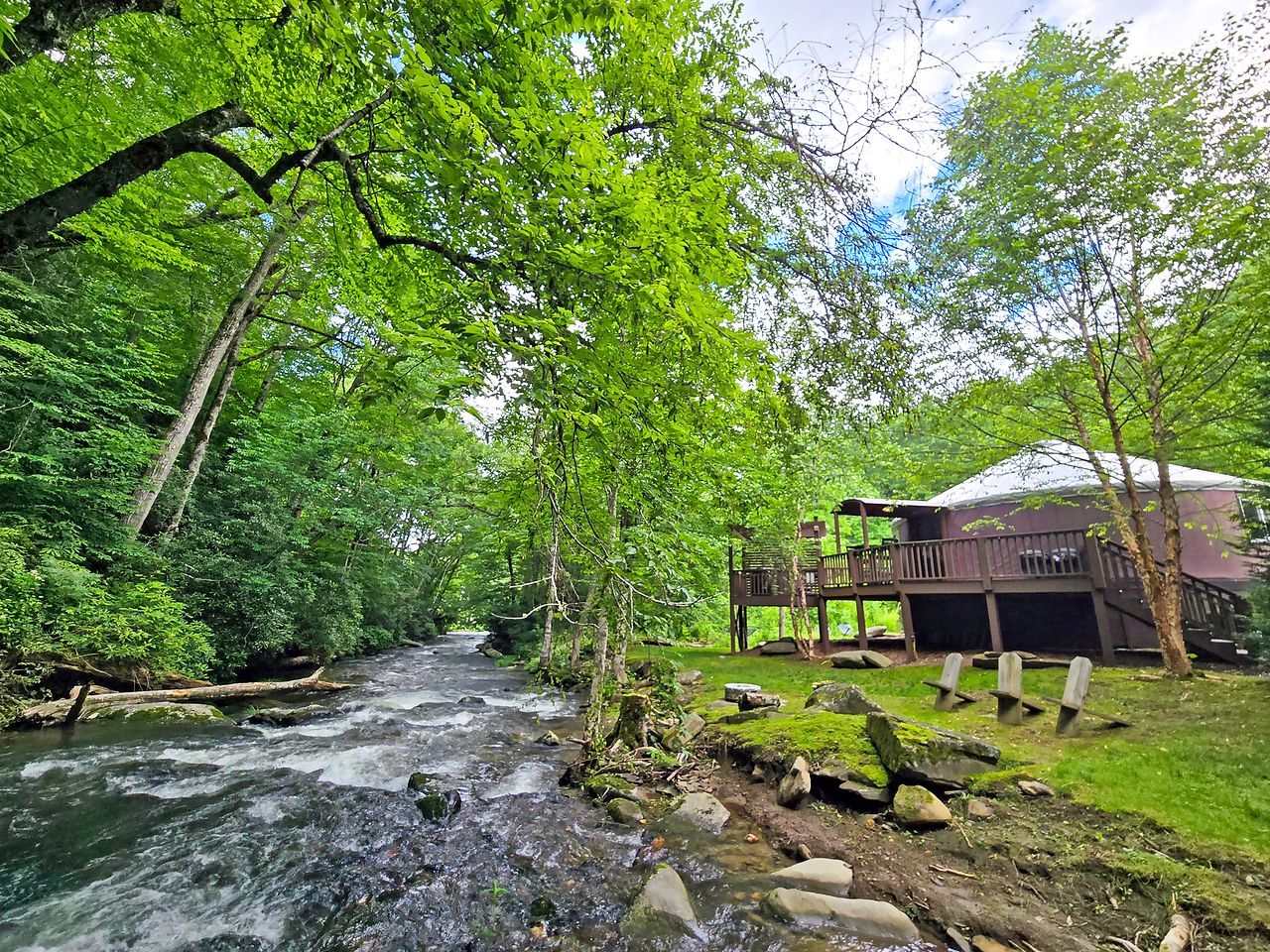 A river flowing through a forest with a wooden structure and a covered area.