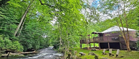 A river flowing through a forest with a wooden structure and a covered area.