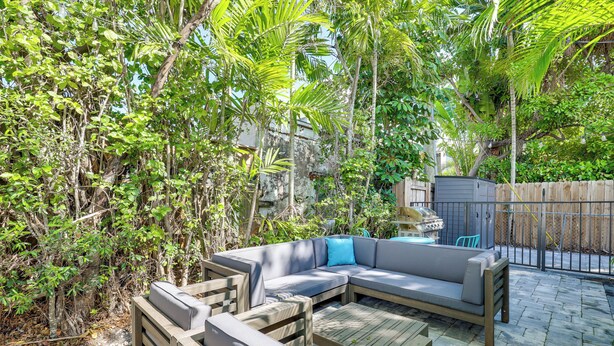 Une terrasse extérieure avec un canapé modulable, une table basse en bois et un barbecue.