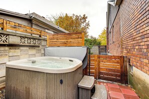A hot tub in a backyard with a wooden fence and a brick wall. - Ski, Soak & Explore! Central Parkside SLC Apt (Salt Lake City)