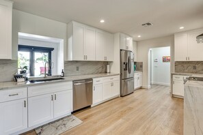 A modern kitchen with white cabinetry, stainless steel appliances, and a marble backsplash. - Sports Court + Hot Tub: Luxe Scottsdale Retreat! (Scottsdale)