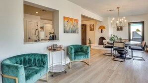 Una sala de estar moderna con una mesa de comedor redonda, dos sillones de terciopelo verde, una mesita auxiliar y un espejo grande.