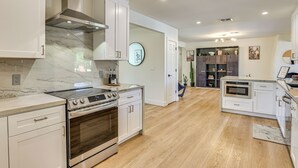 Una cocina moderna con armarios blancos, estufa de acero inoxidable y una salpicadera de mármol.