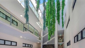 A spacious atrium with hanging greenery, a central seating area, and a modern architectural design.