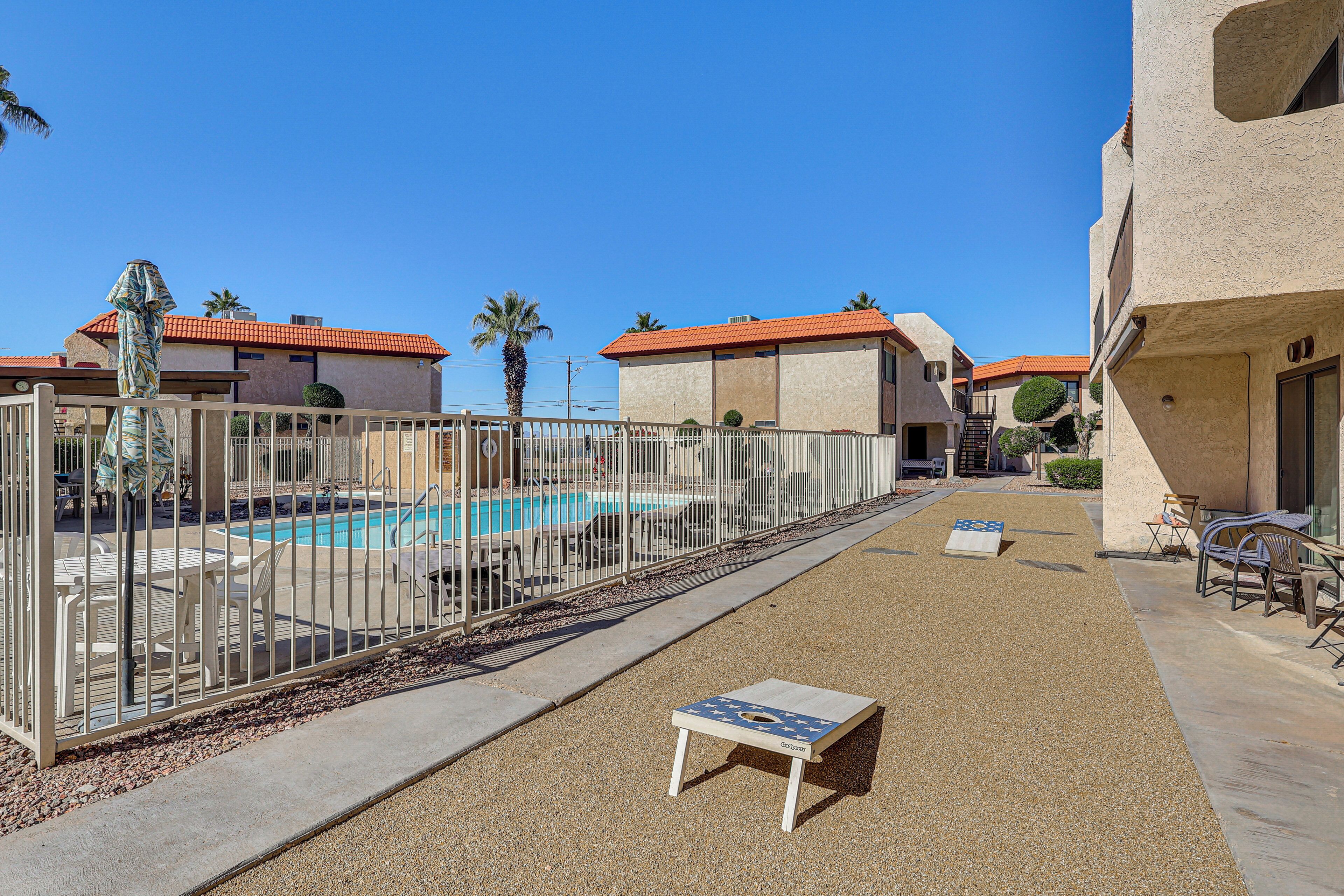 Un espace piscine doté d’une terrasse entourée d’une clôture, de chaises longues et d’une petite table avec une plaque.