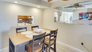 A dining area with a wooden table, four chairs, a ceiling fan, and a wall-mounted mirror. - Pool, Lake & Sun! Havasu Hot Spot By London Bridge (Lake Havasu City)
