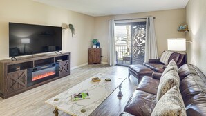 A living room with a flat-screen TV, a fireplace, a leather sofa, and a sliding glass door to the outdoors. - Pool, Lake & Sun! Havasu Hot Spot By London Bridge (Lake Havasu City)