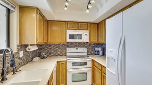 A kitchen with wooden cabinets, a white refrigerator, a double oven, a microwave, and a sink. - Pool, Lake & Sun! Havasu Hot Spot By London Bridge (Lake Havasu City)