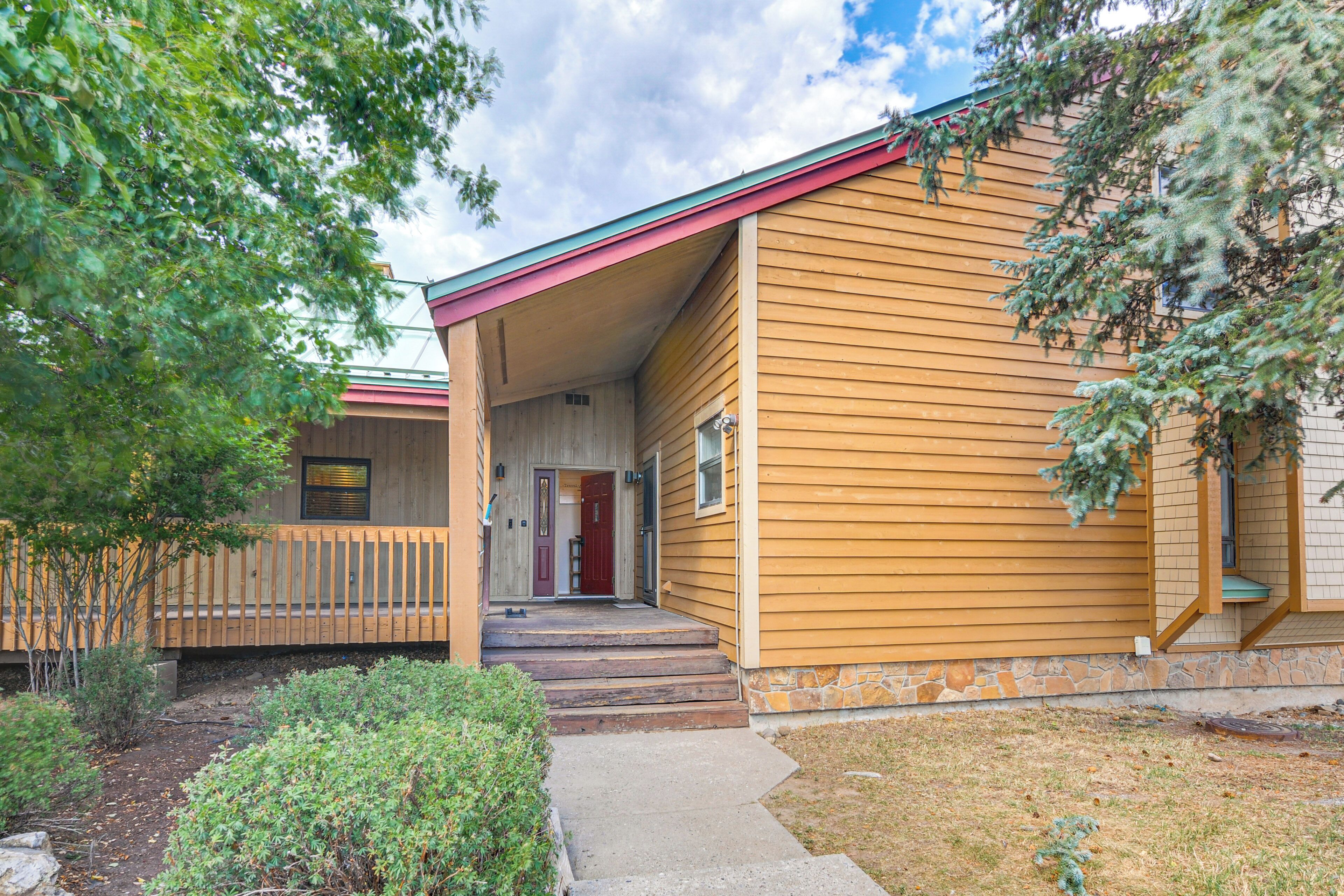 A two-story building with a covered porch and a red door.