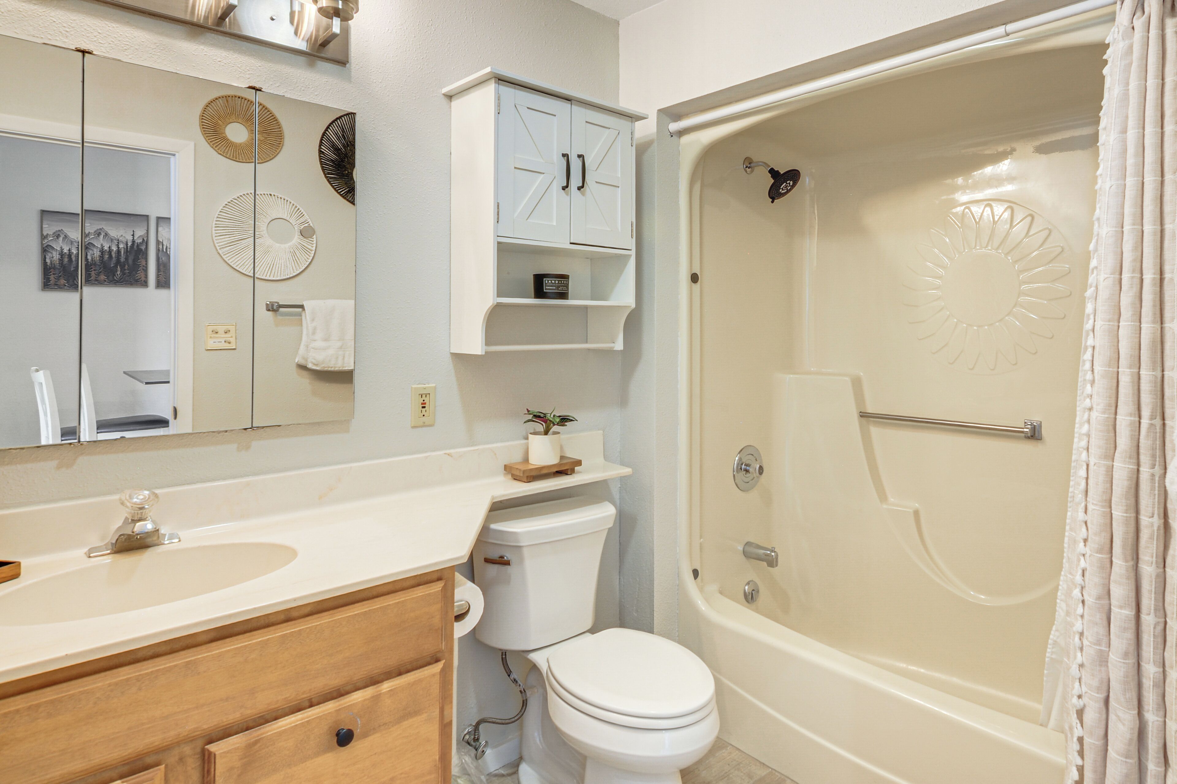Un baño con lavamanos blanco, espejo, inodoro y bañera.