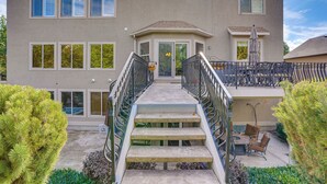 A two-story house with a central entrance, a covered patio with outdoor furniture, and a staircase with metal railings. - Upscale Group Getaway in Orem w/ Private Hot Tub (Orem)
