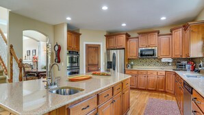 A spacious kitchen with wooden cabinets, stainless steel appliances, and a granite countertop. - Upscale Group Getaway in Orem w/ Private Hot Tub (Orem)