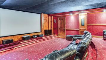 A theater with a red carpet, leather seating, a screen, and wooden paneling.
