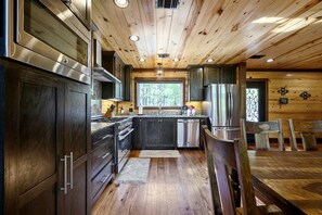 Une cuisine moderne avec des meubles de couleur bois foncé, des appareils électroménagers en acier inoxydable et un plafond en bois.