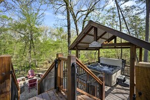 A wooden deck with a hot tub, a covered seating area, and a sign reading 'Woodshed Cabin.' - Creekside Cabin Perfect for Family Getaways in Broken Bow, Oklahoma (Broken Bow)