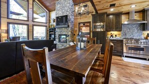A wooden interior with a stone fireplace, a dining table, and modern kitchen appliances. - Creekside Cabin Perfect for Family Getaways in Broken Bow, Oklahoma (Broken Bow)