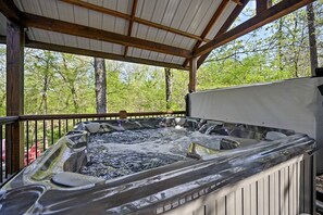 Ein Whirlpool mit Holzterrasse und Metallgeländern, umgeben von Bäumen.