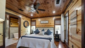 A wooden-paneled bedroom with a bed, a ceiling fan, and a sign that reads 'Grateful Heart.' - Creekside Cabin Perfect for Family Getaways in Broken Bow, Oklahoma (Broken Bow)