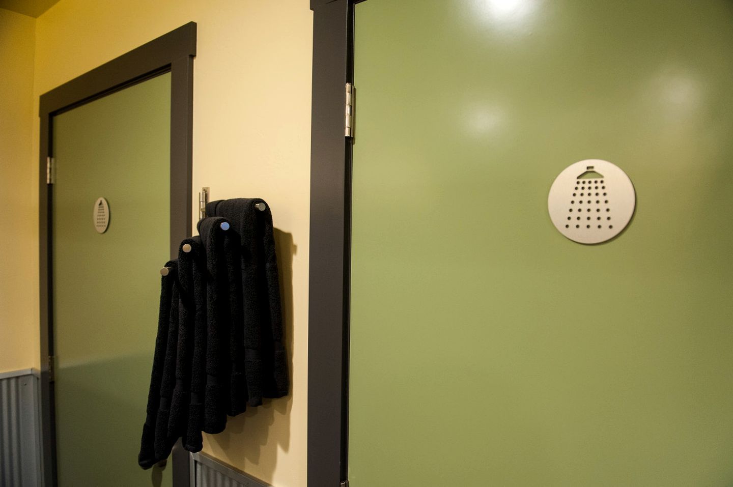 A room with a door, a towel rack with towels, and a smoke detector on the wall.