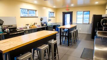 A modern kitchen with a central island, bar stools, stainless steel appliances, and windows providing natural light.