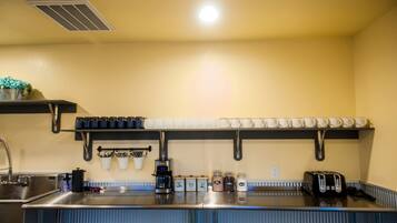 A kitchen with a stainless steel countertop, a coffee machine, a toaster, and jars of condiments.