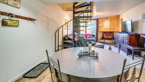 A dining area with a round table, chairs, a staircase, a fireplace, and a television. - Ski Copper Mountain! Alpine-chic Condo w/ Hot Tub (Copper Mountain)