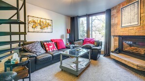 A modern living room with a leather sofa, glass coffee table, fireplace, and a staircase. - Ski Copper Mountain! Alpine-chic Condo w/ Hot Tub (Copper Mountain)