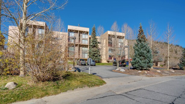 A modern building with multiple floors, a parking area, and surrounding trees. - Ski Copper Mountain! Alpine-chic Condo w/ Hot Tub (Copper Mountain)