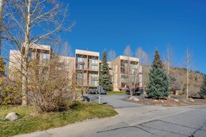 A modern building with multiple floors, a parking area, and surrounding trees. - Ski Copper Mountain! Alpine-chic Condo w/ Hot Tub (Copper Mountain)