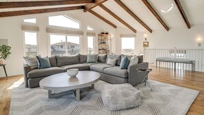 Ein geräumiges Wohnzimmer mit einer Eckcouch, einem runden Couchtisch und einem gemusterten Teppich.