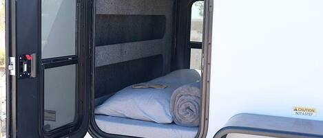 A vehicle with an open cargo area containing a rolled-up blanket and a pillow.