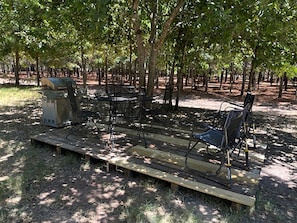 A picnic setup with a table and chairs in a wooded area. - Dream Glamping in Texas in this Cozy, Pet-Friendly Cabin in Bastrop, TX (Bastrop)