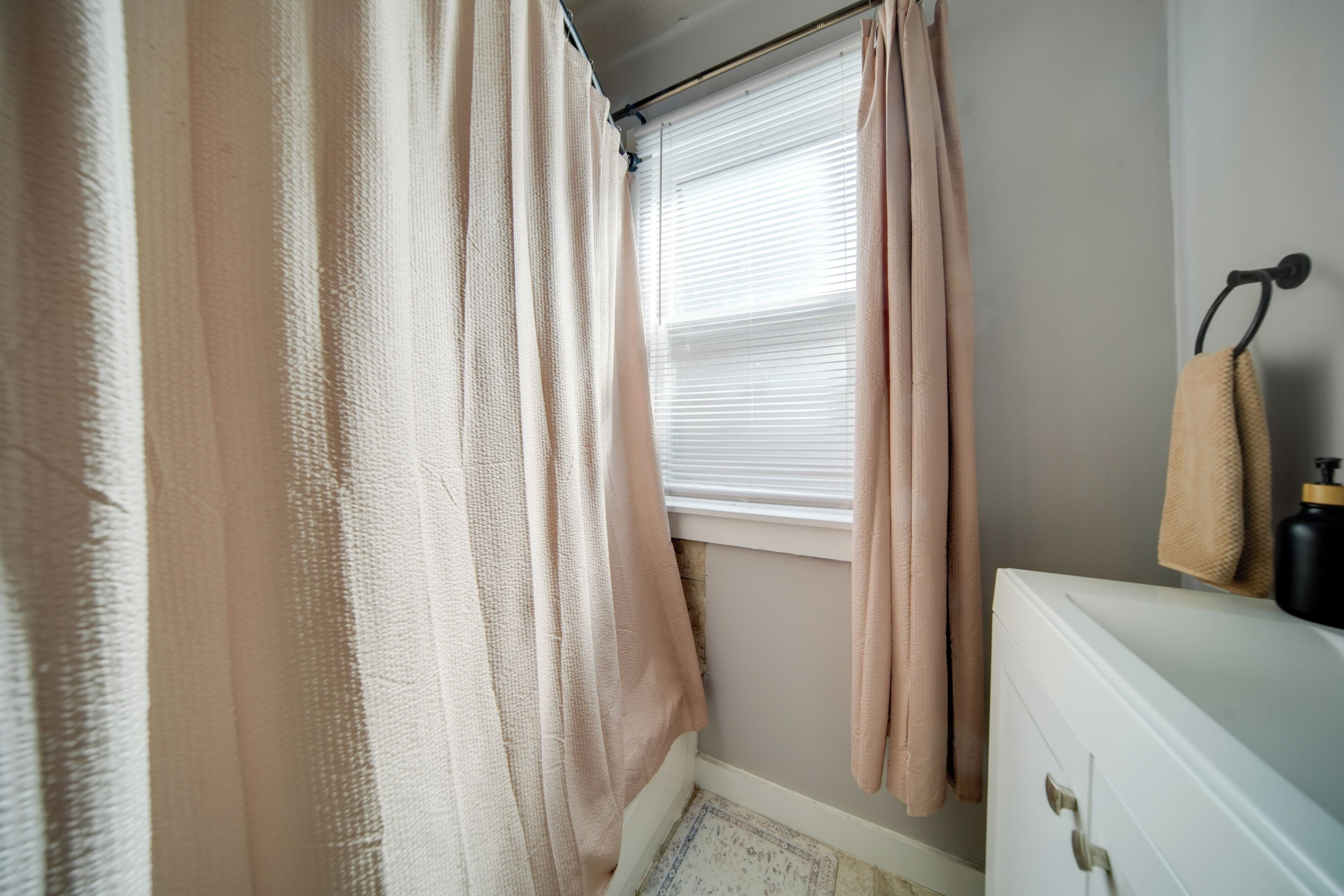 A bathroom with a window, a towel rack, and a white cabinet.