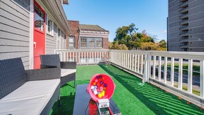 An outdoor patio with wicker furniture, a red bucket filled with balls, and a sign indicating a golf course nearby. - Deck, Pool Table! Walkable Cleveland Heights Apt (Cleveland Heights)