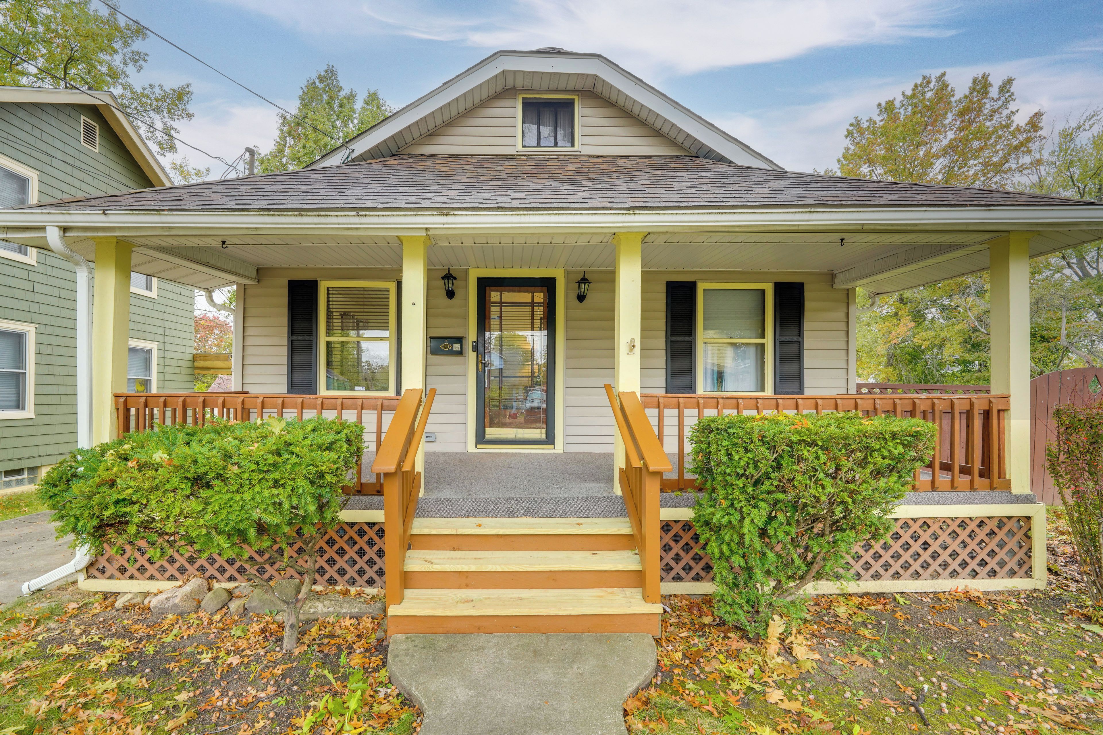 A two-story house with a front porch, wooden steps, and a small front yard.