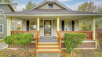 A two-story house with a front porch, wooden steps, and a small front yard.