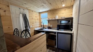 Une cuisine compacte avec des murs en bois, un four à micro-ondes, un évier et un petit réfrigérateur.