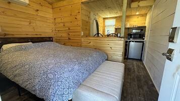 Ein Holzblockhaus-Interieur mit Bett, Bank, Küchenzeile und einer Tür.