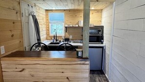 Une petite cabine comprenant un coin cuisine, un espace repas et un coin nuit.