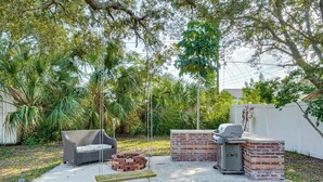 A backyard with a brick barbecue, a wicker sofa, and a fire pit. - Convenient Oasis in St Pete, 4 Mi to Pier & Dtwn! (St. Petersburg)