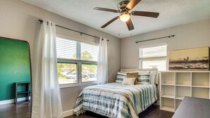 A bedroom with a bed, two windows with curtains, a ceiling fan, and a painting on the wall. - Convenient Oasis in St Pete, 4 Mi to Pier & Dtwn! (St. Petersburg)
