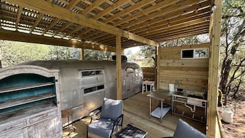 A covered outdoor area with a wood-burning stove, seating, and a table.