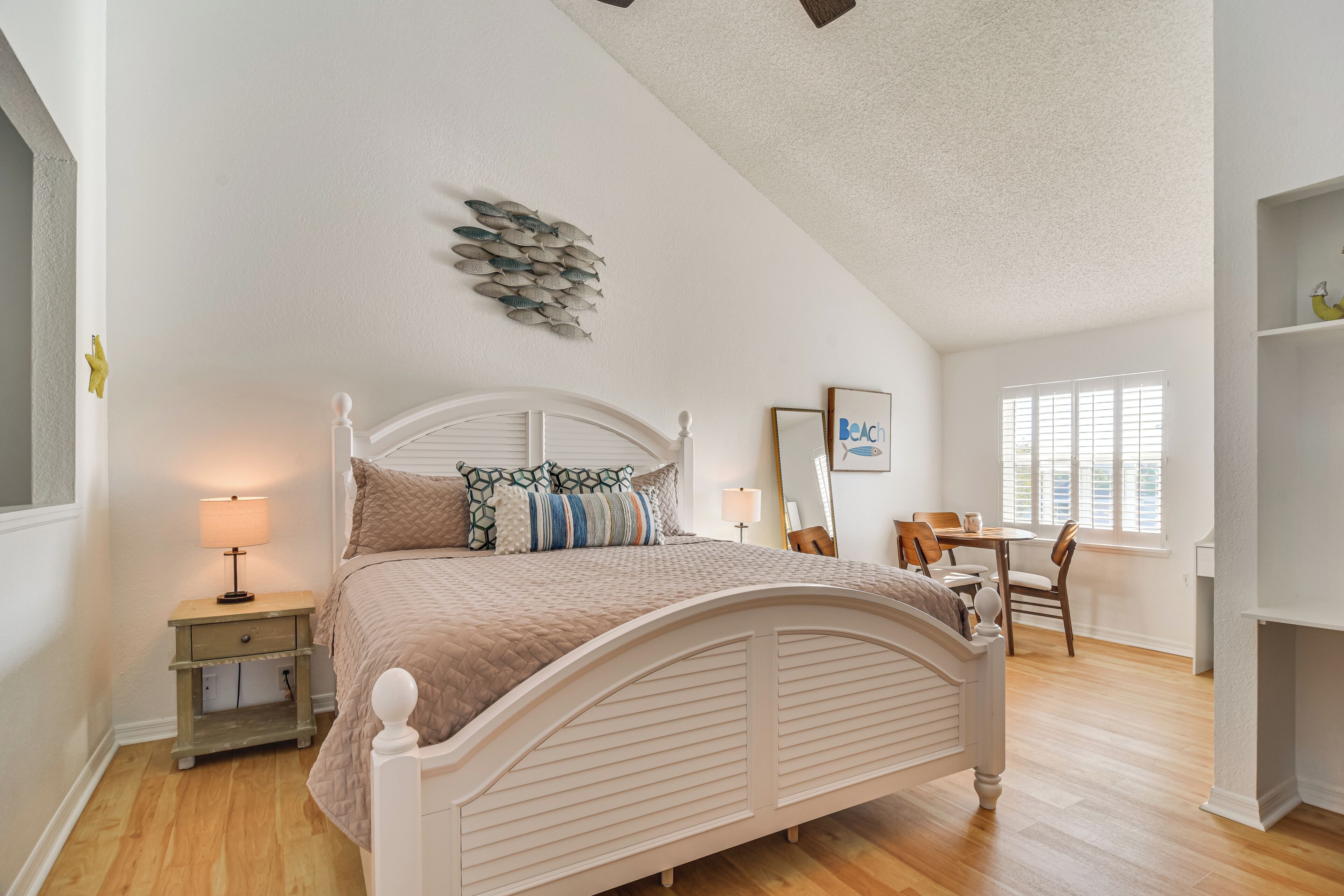 A bedroom with a bed, bedside table, lamp, and a wall decoration.