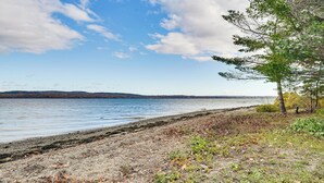 A lakeside view with a sandy shore, trees, and distant hills. - River Access! Penobscot Retreat 5 Mi to Fort Knox (Stockton Springs)